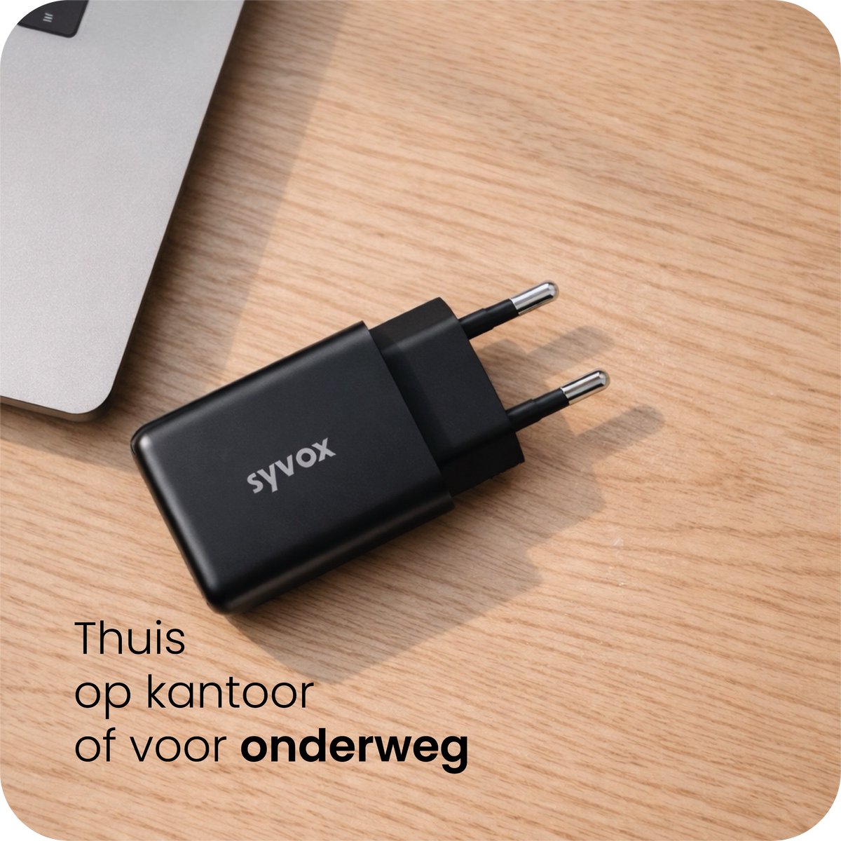 SYVOX Power-wandoplader uit de laadset naast een laptop op een houten bureau